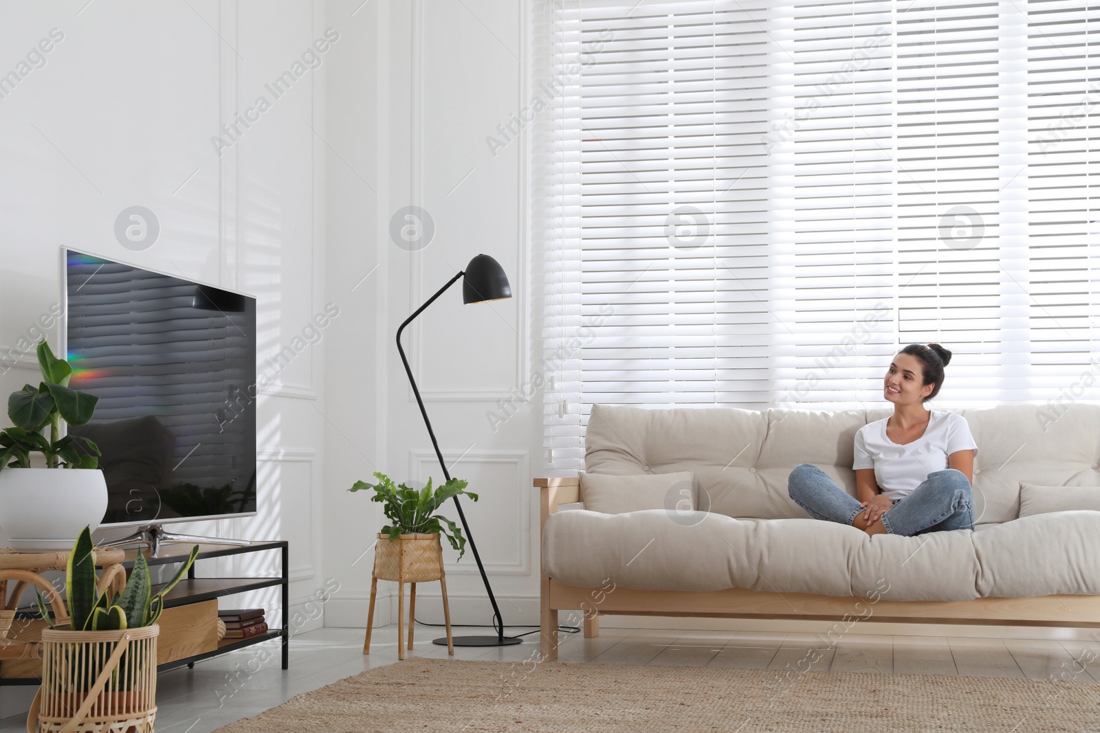 Photo of Woman watching television at home. Living room interior with TV on stand