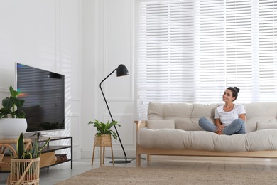 Woman watching television at home. Living room interior with TV on stand