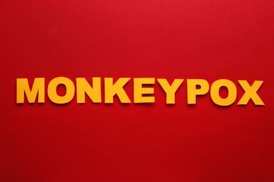 Photo of Word Monkeypox made of paper letters on red background, top view