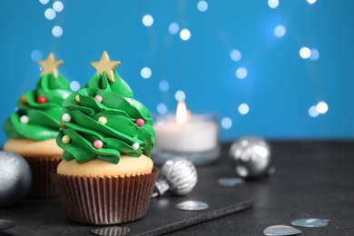 Christmas tree shaped cupcakes and decor on black table