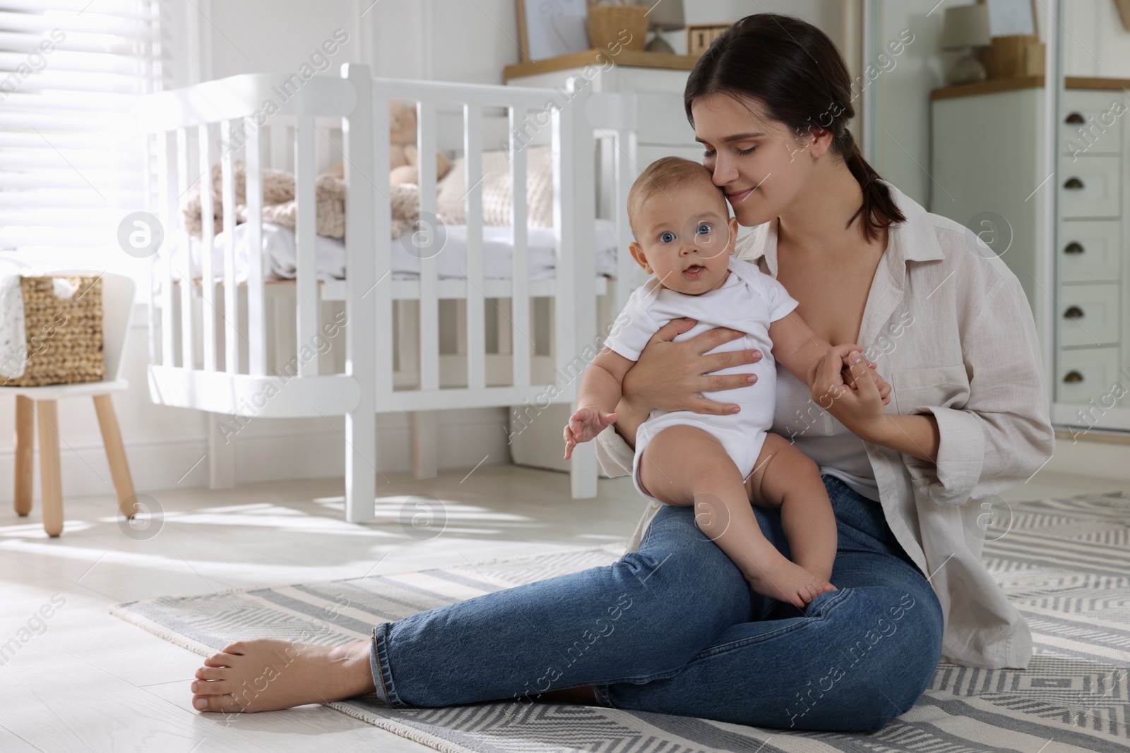 Photo of Happy young mother with her baby in nursery. Space for text