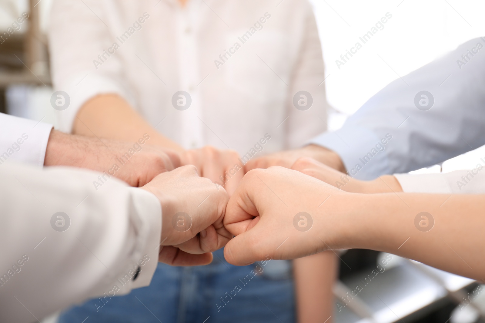 Photo of People holding fists together in office, closeup