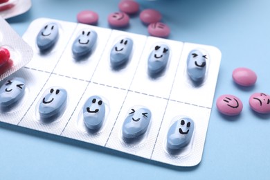 Photo of Blister and antidepressant pills with emotional faces on light blue background, closeup