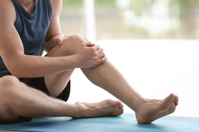 Photo of Man in sportswear suffering from knee pain at gym, closeup