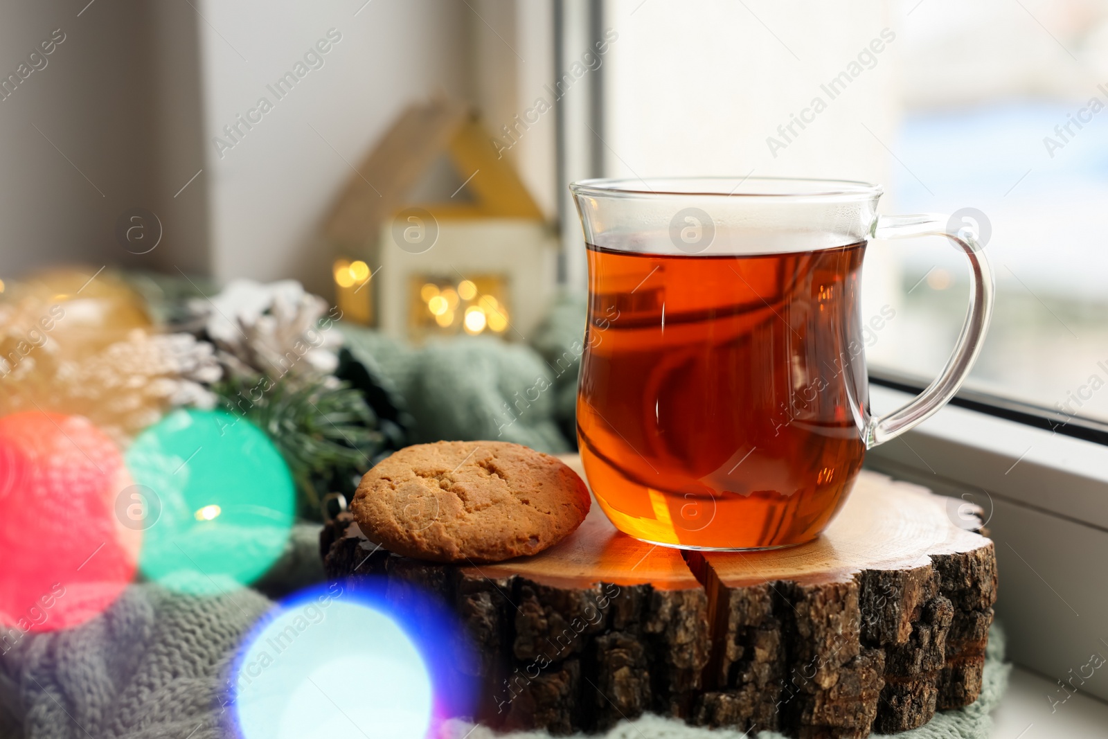Photo of Cup of tea, cookie and Christmas decor on windowsill indoors