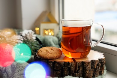 Photo of Cup of tea, cookie and Christmas decor on windowsill indoors