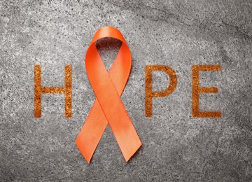 Image of Orange ribbon and word HOPE on grey background, top view 