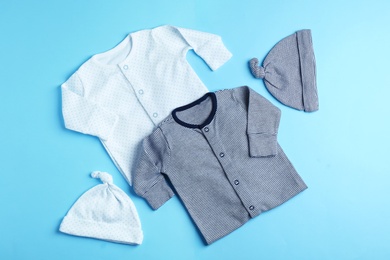 Photo of Flat lay composition with caps and bodysuits on color background. Baby accessories