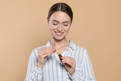 Young woman with bottle of essential oil on beige background