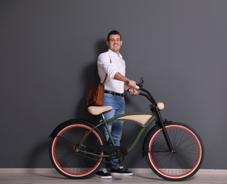 Photo of Portrait of handsome young man with bicycle near color wall