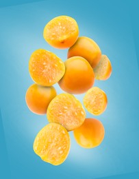 Ripe orange physalis fruits falling on light blue background