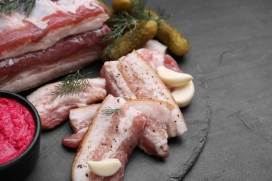 Photo of Tasty pork fatback with spices, garlic and dill on black table, closeup