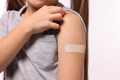 Photo of Girl with sticking plaster on arm after vaccination against white background, closeup