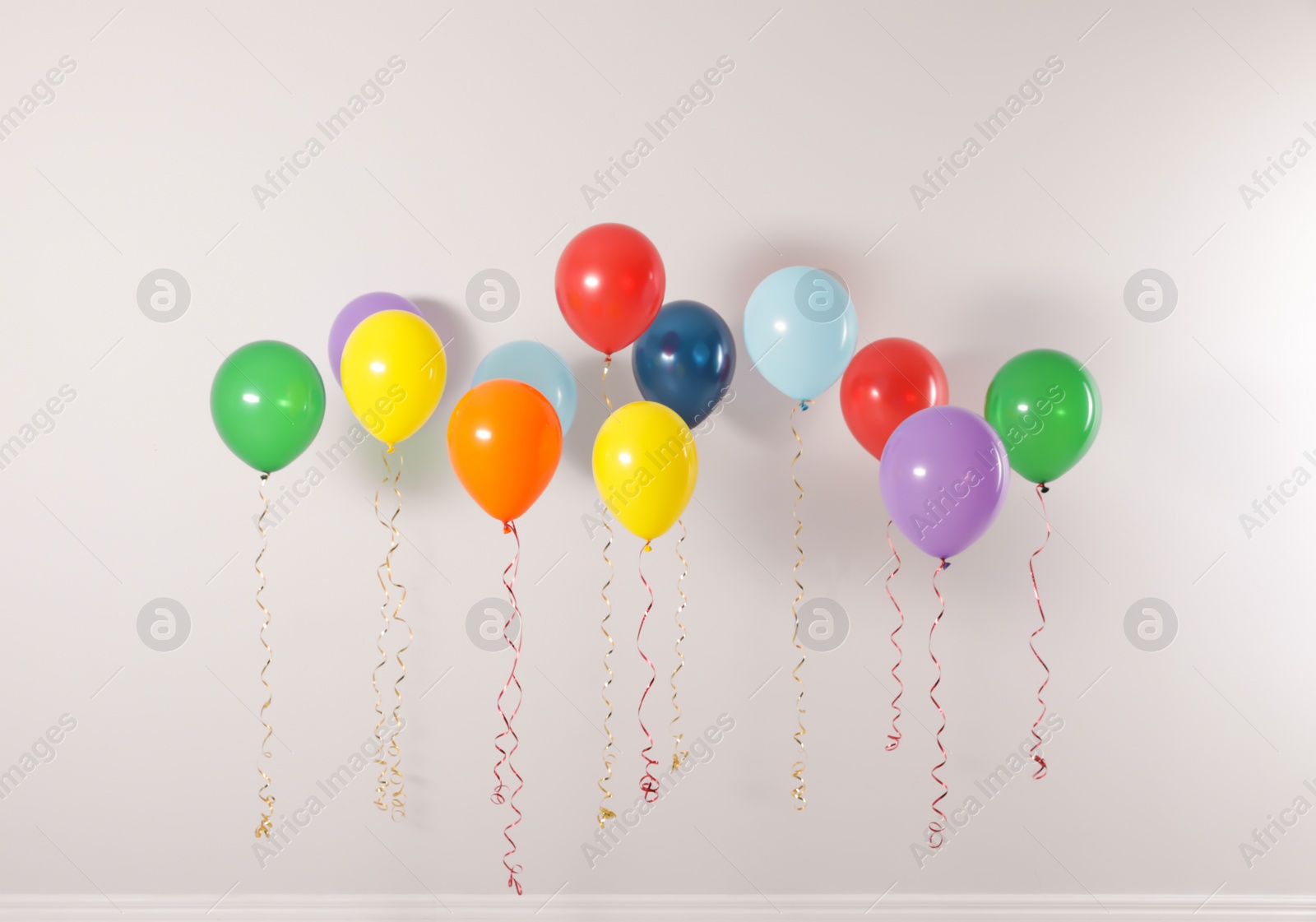 Photo of Different bright balloons on light background. Celebration time