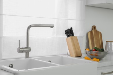 Photo of Modern sink and water tap on kitchen counter. Interior design