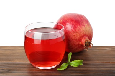 Photo of Refreshing pomegranate juice in glass, leaves and fruit on wooden table against white background