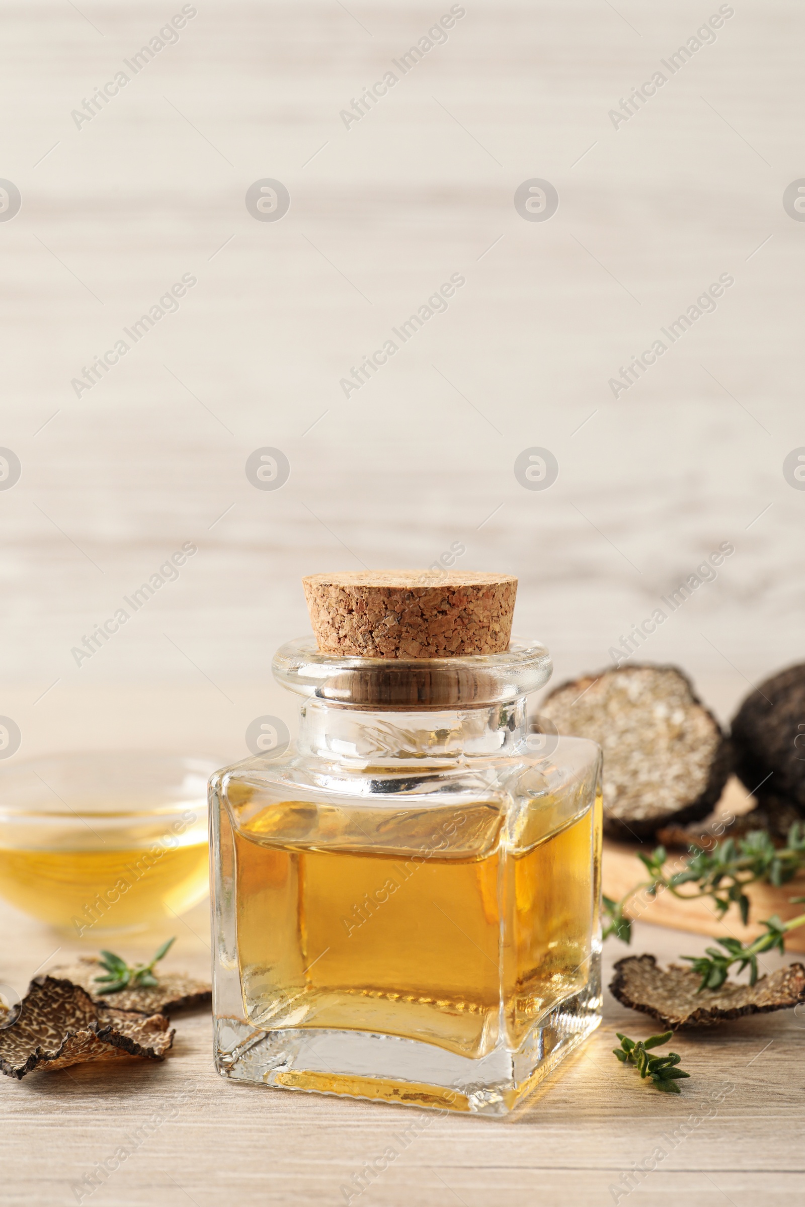 Photo of Fresh truffle oil and thyme on wooden table, space for text