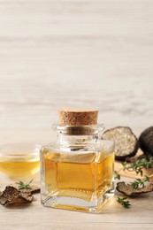 Fresh truffle oil and thyme on wooden table, space for text
