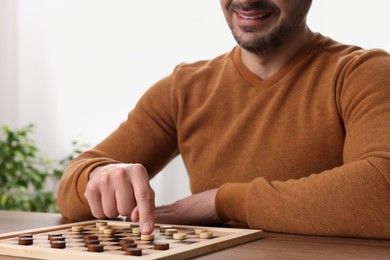 Man playing checkers at table in room, closeup