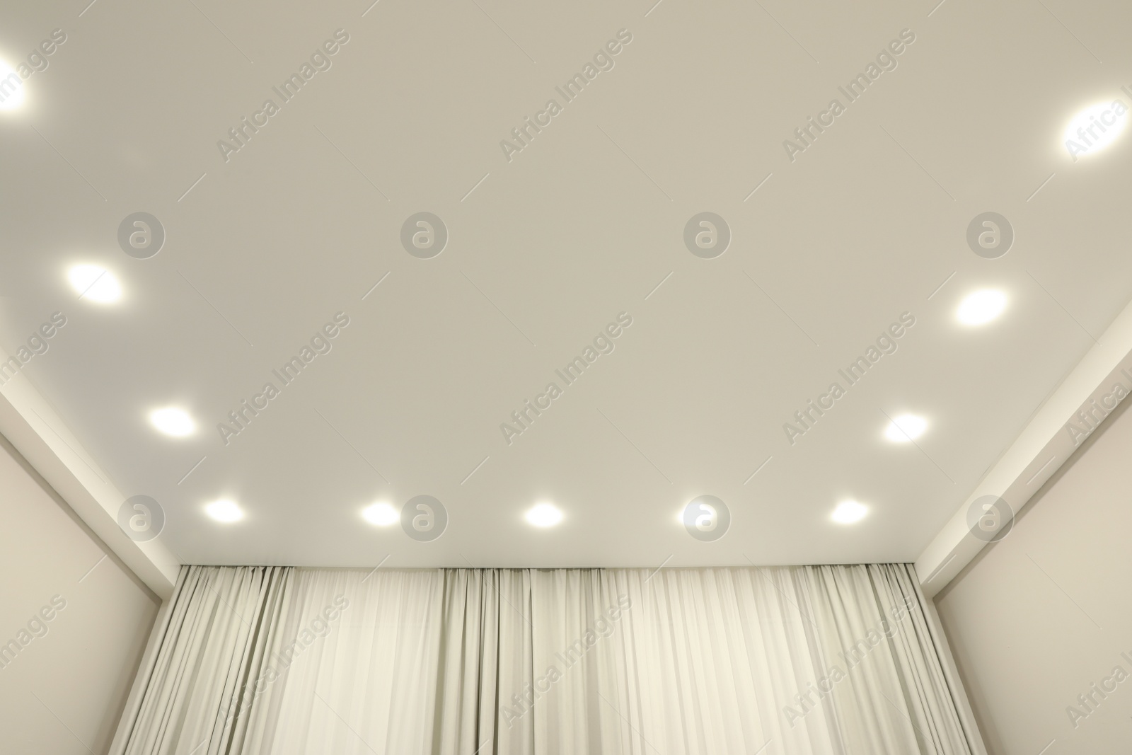 Photo of White stretch ceiling with spot lights in room