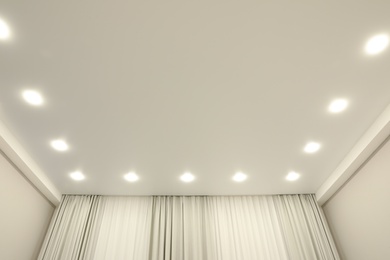 Photo of White stretch ceiling with spot lights in room