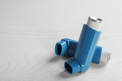 Photo of Asthma inhalers and space for text on white wooden background
