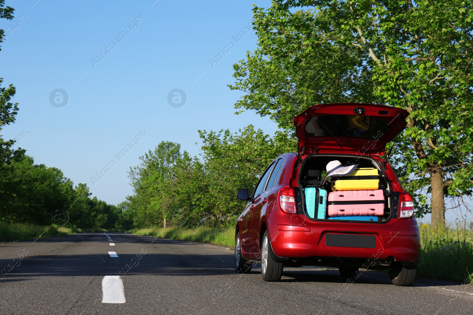 Photo of Family car with open trunk full of luggage on highway. Space for text