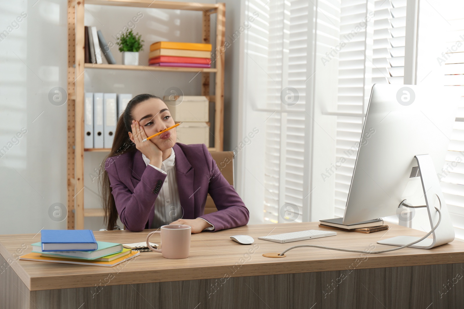 Photo of Lazy employee playing with pencil at table in office