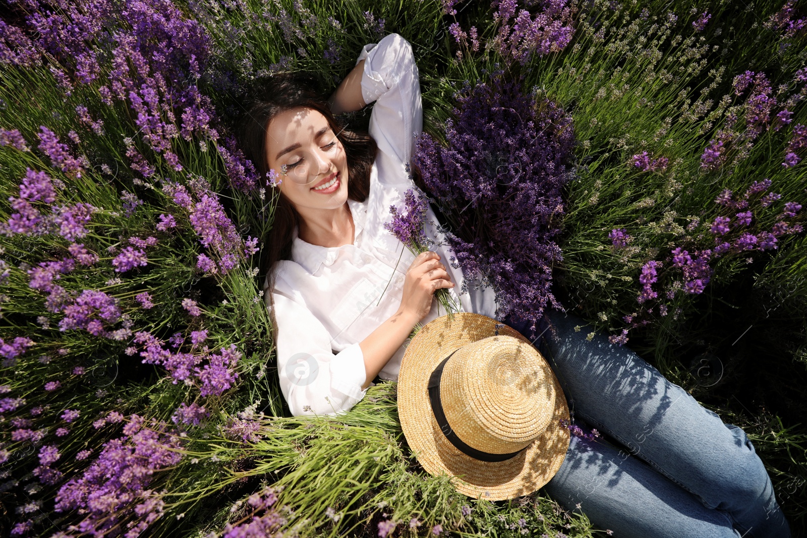 Photo of Young woman lying in lavender field on summer day