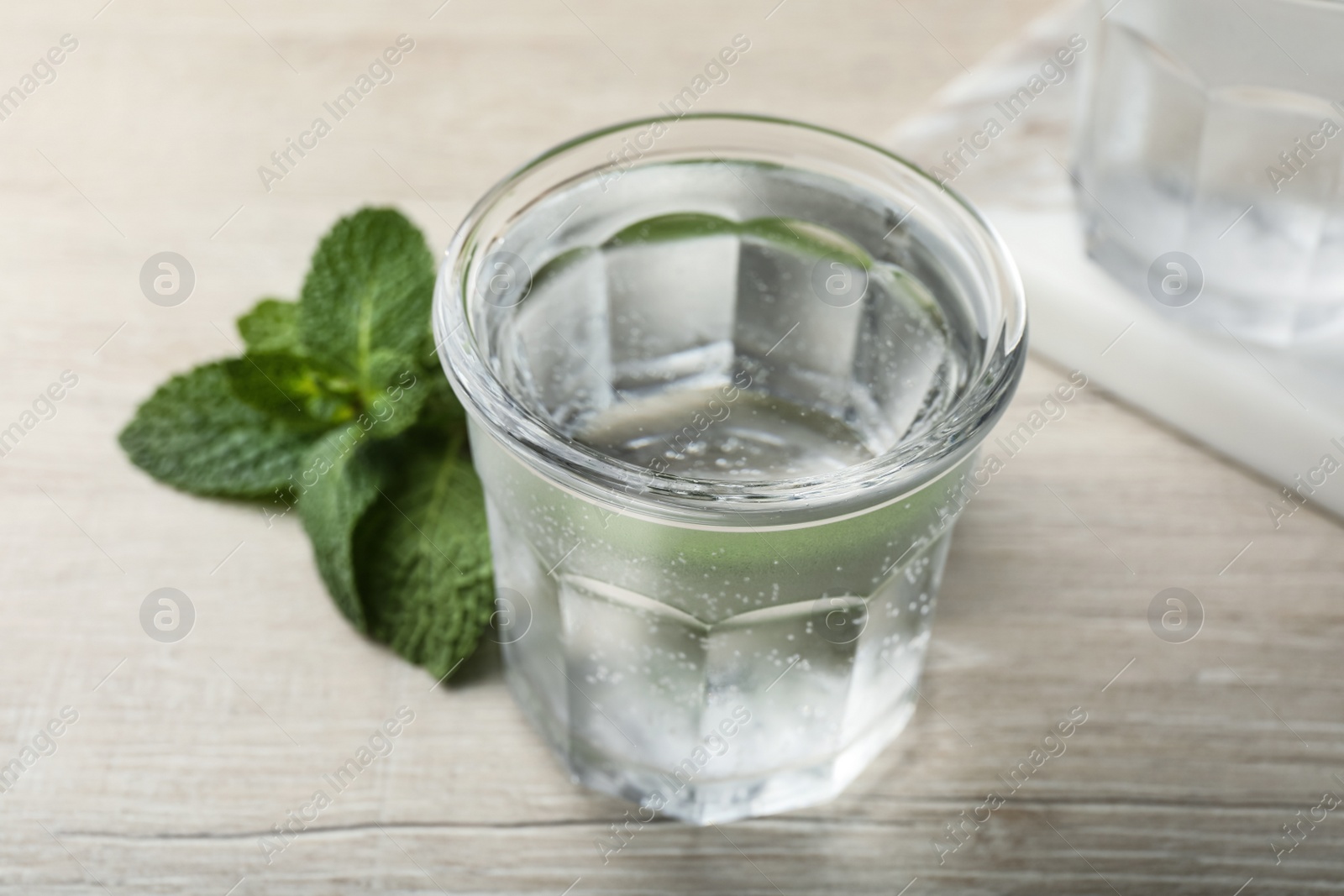 Photo of Glass of soda water and mint on white wooden table