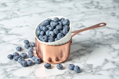 Photo of Cookware with juicy and fresh blueberries on marble table