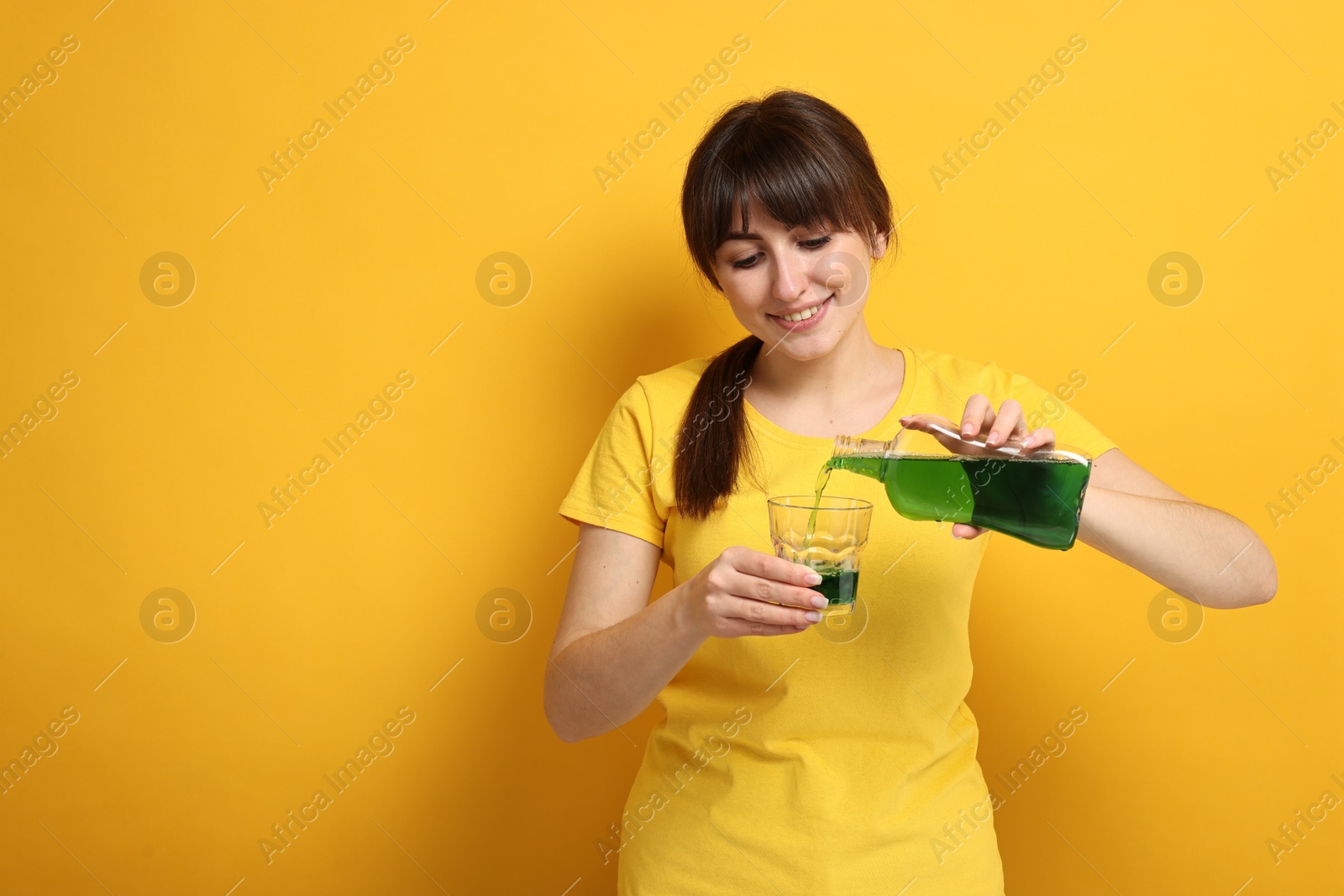 Photo of Young woman using mouthwash on yellow background, space for text