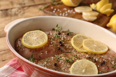 Photo of Chicken breasts with lemon and rosemary on wooden table, closeup