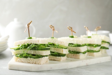 Board with traditional English cucumber sandwiches on table