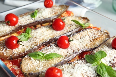 Photo of Baked eggplant with tomatoes, cheese and basil in dishware, closeup