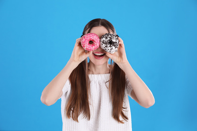 Photo of Beautiful young woman with donuts on light blue background