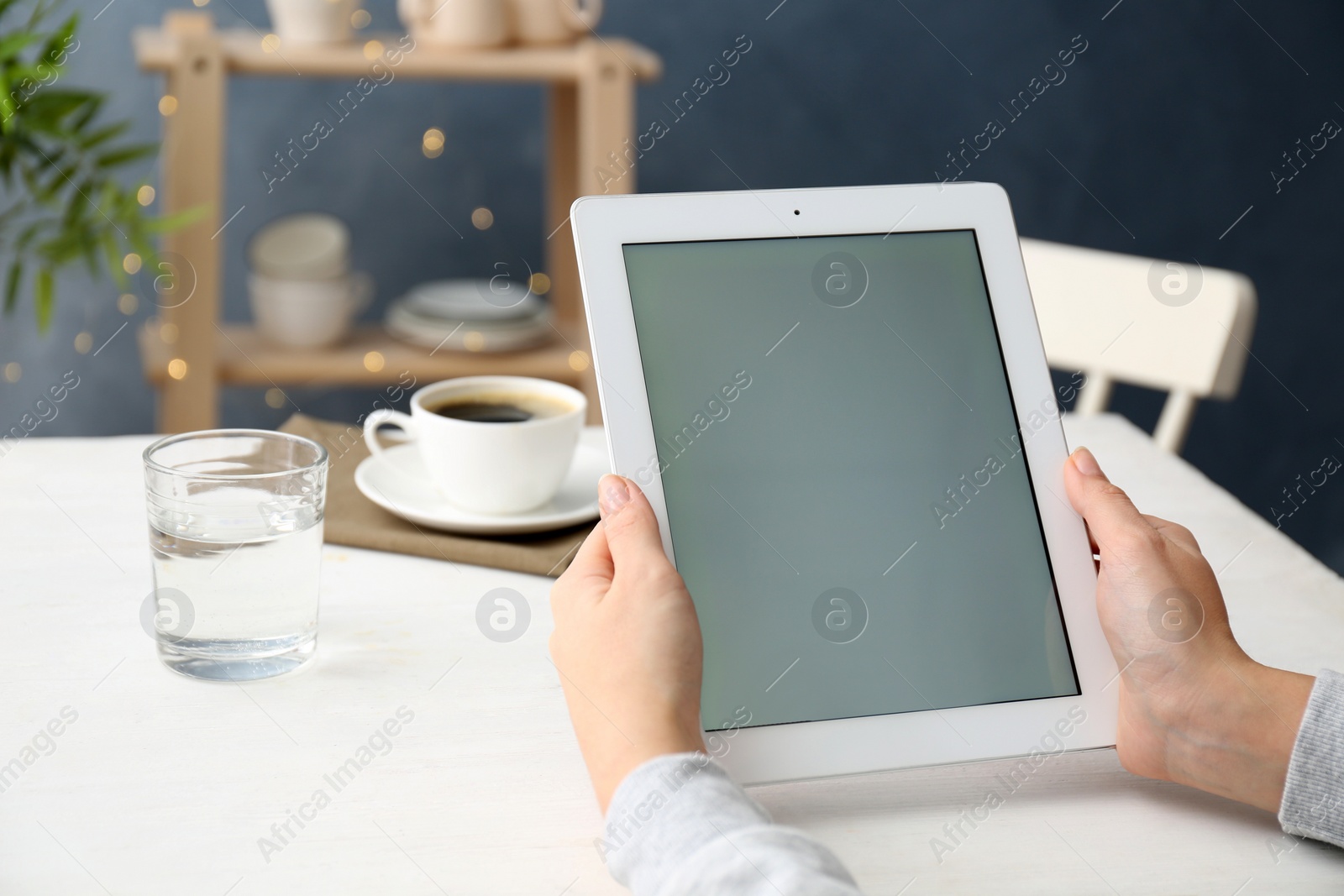 Photo of Young woman using new modern tablet in kitchen, closeup