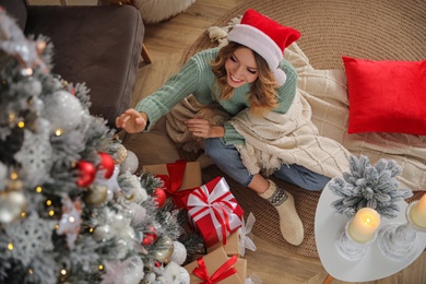 Young woman decorating Christmas tree at home, above view