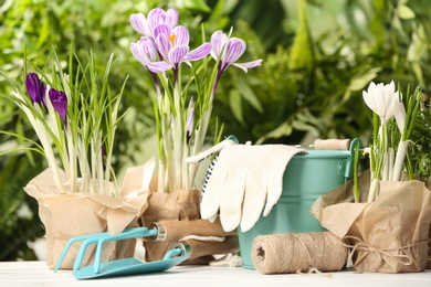 Photo of Blooming flowers and gardening equipment on table outdoors