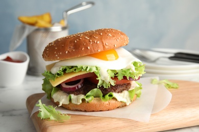 Tasty burger with fried egg on wooden board