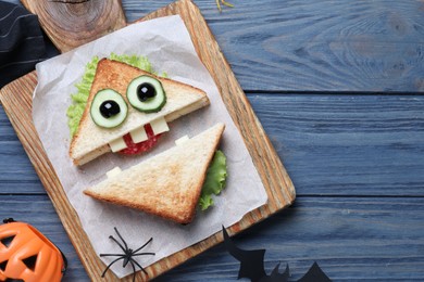 Photo of Cute monster sandwich served on blue wooden table, flat lay with space for text. Halloween party food