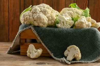 Crate with cut and whole cauliflowers on wooden table