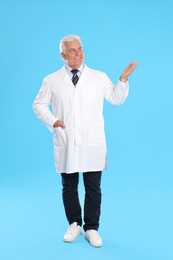 Photo of Happy senior man in lab coat on light blue background