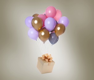 Image of Many balloons tied to gift box on color background