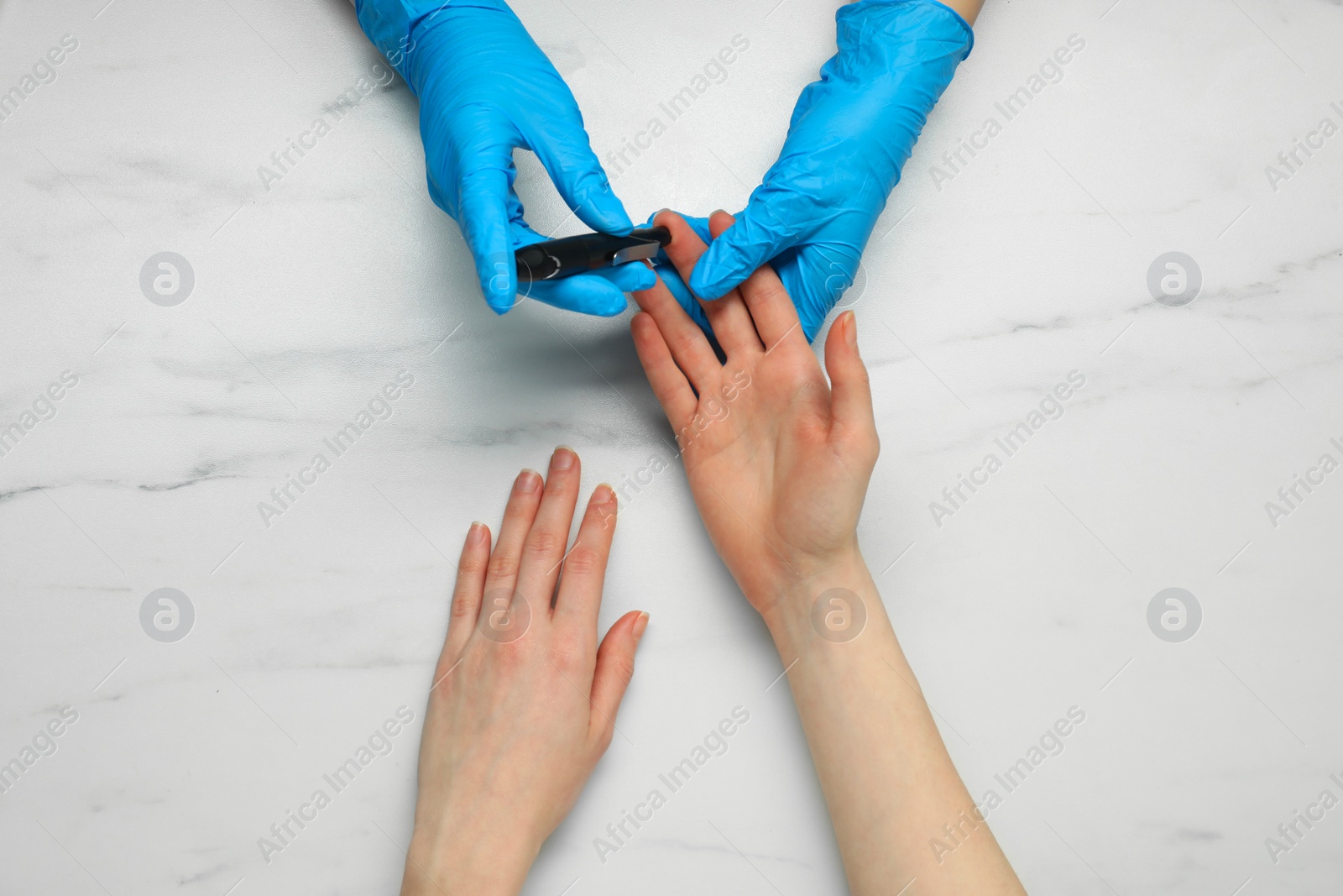 Photo of Diabetes. glucose testing. Doctor using lancet pen at white marble table, top view