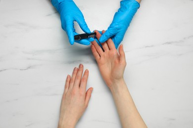 Diabetes. glucose testing. Doctor using lancet pen at white marble table, top view