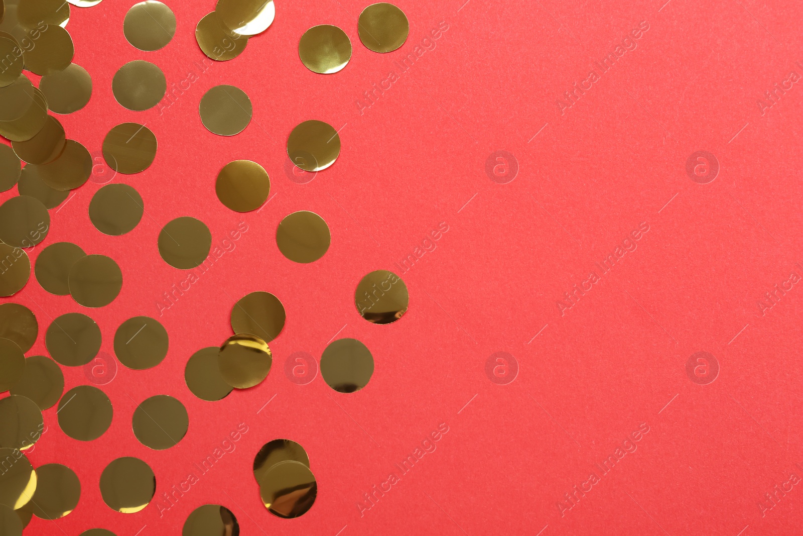 Photo of Shiny golden confetti on red background, flat lay. Space for text