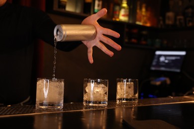 Photo of Bartender pouring energy drink into glass at counter in bar, closeup