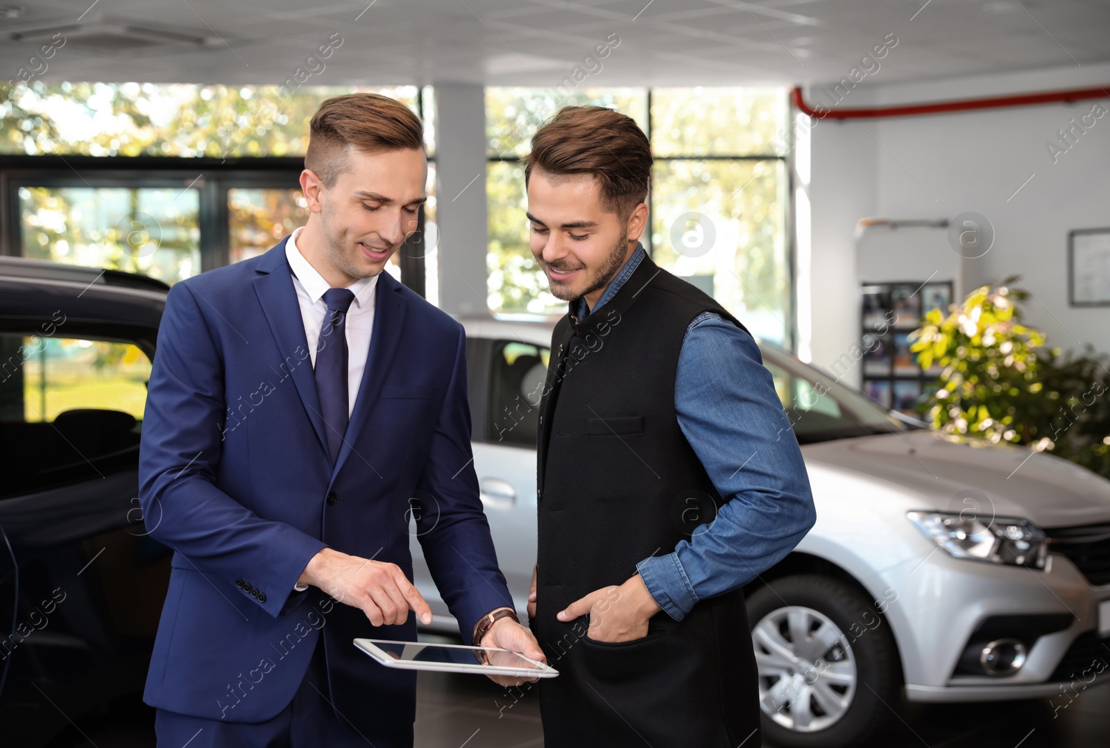 Photo of Young car salesman working with client in dealership