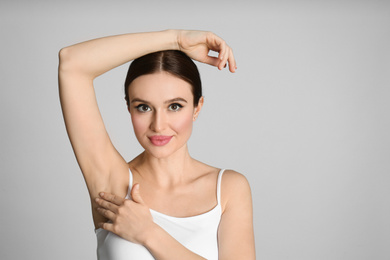 Photo of Young beautiful woman showing armpit with smooth clean skin on light blue background